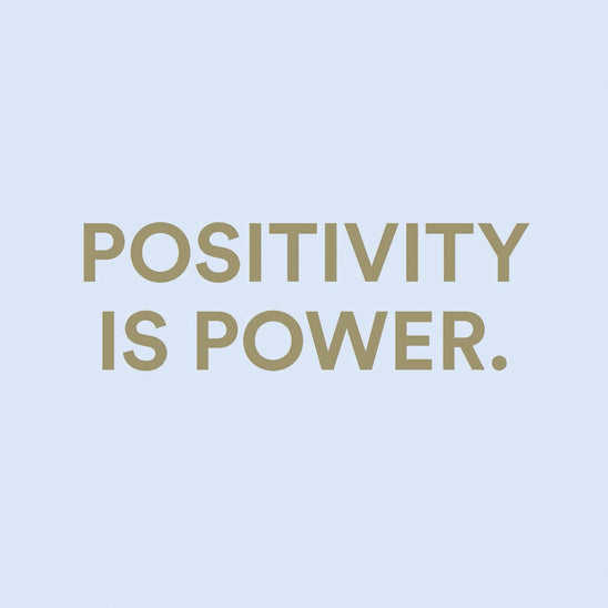 Inspirational quote “Positivity is power” on a soft blue background, representing wellness, self-care, motivation, and the uplifting message of Positivity in a Bottle by The Heart Company
