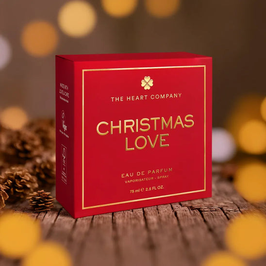 Christmas Love vegan eau de parfum packaging by The Heart Company, elegant red and gold perfume box displayed in a festive holiday setting with warm lights, cruelty-free fragrance gift