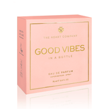 Vegan “Good Vibes in a Bottle” eau de parfum packaging by The Heart Company, featuring a soft pink luxury box with gold lettering, a fruity, floral, sweet gourmand fragrance, cruelty-free perfume designed to uplift mood and spread positive energy.